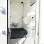 Toilet trailer booth with urinal, door open.
